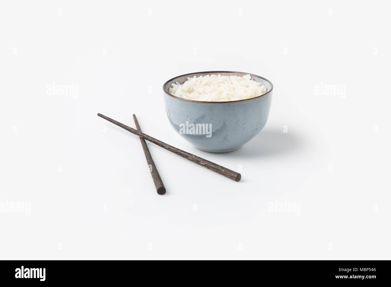 Bol de riz avec des baguettes sur la table blanche Banque D'Images