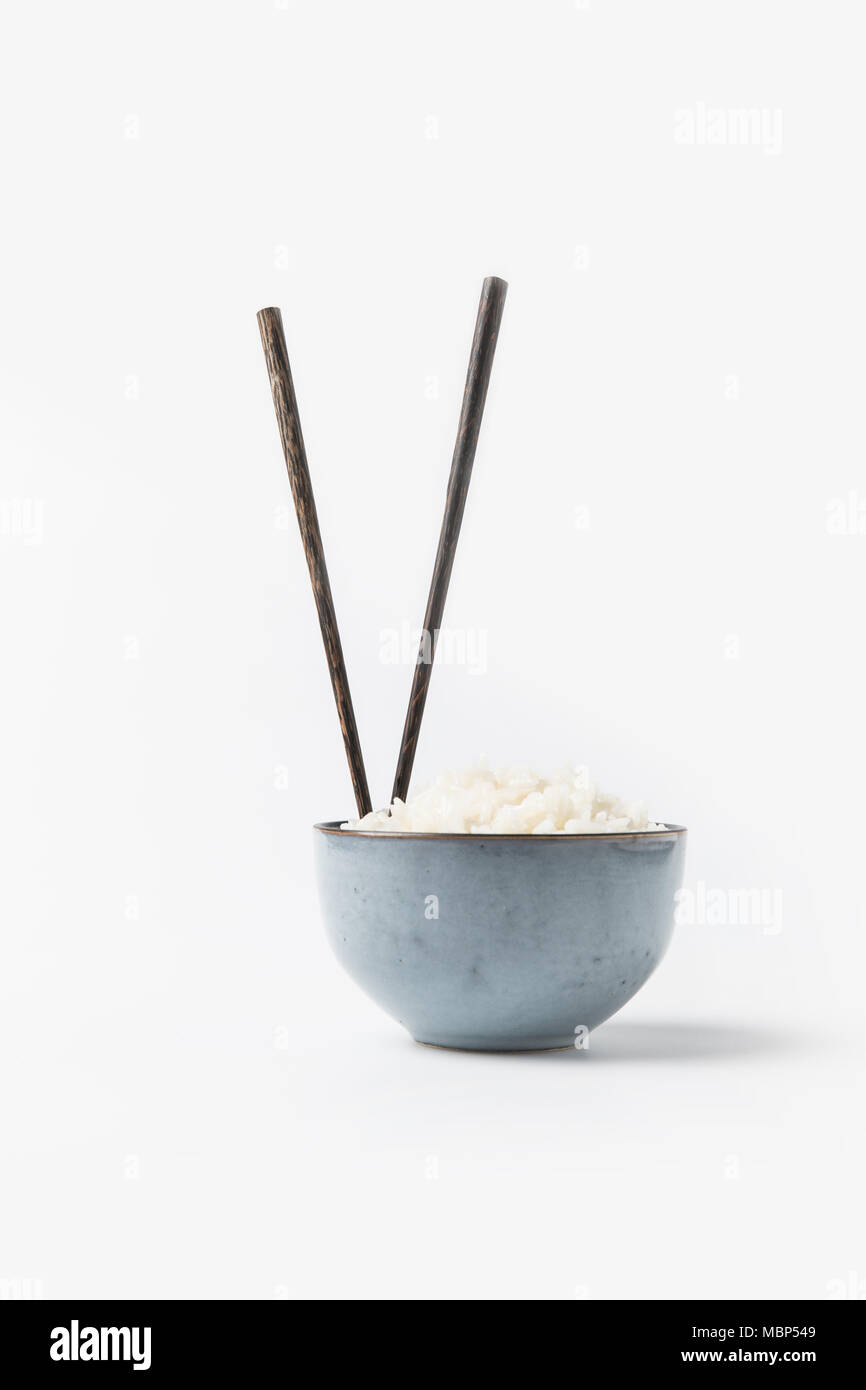 Bol de riz fraîchement cuit avec des baguettes sur la surface blanche Banque D'Images