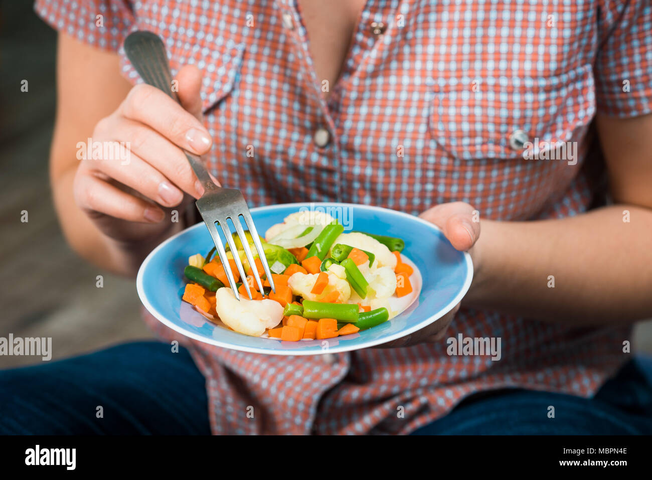 Fille avec une assiette de légumes en mains Banque D'Images