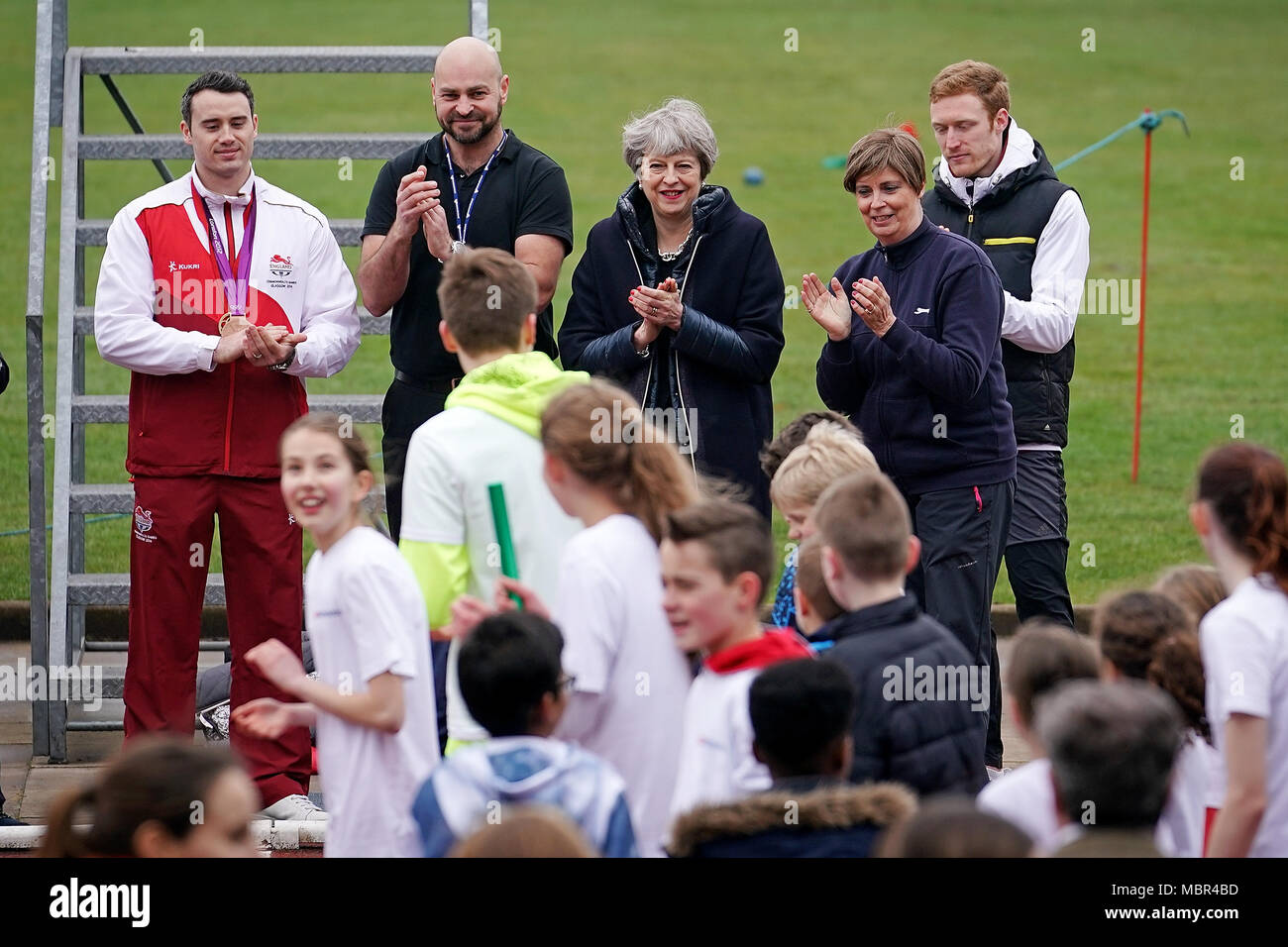 Premier ministre Theresa peut (centre) la montre de jeunes athlètes de prendre part à une course de relais durant sa visite à Alexander Stadium de Perry Park à Perry Barr, Birmingham, qui est réglée à bénéficier d'un investissement de 70 millions de GBP pour la transformer en un lieu de classe mondiale de l'athlétisme en avant de la ville qui accueille les Jeux du Commonwealth de 2022. Banque D'Images