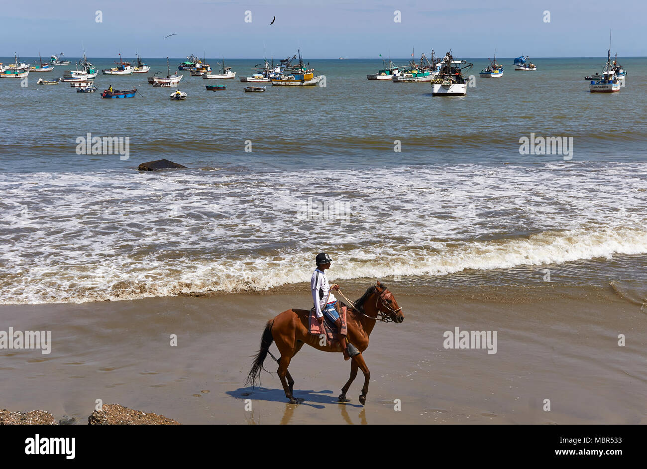 Une personne montant un cheval alezan sur la plage de Mancora, un petit village de pêcheurs situé dans le nord-ouest du Pérou, en Amérique du Sud. Banque D'Images