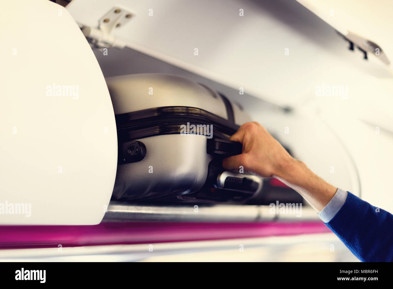 Coffre à la main avec des valises en avion. Mains enlever les bagages à main. Cabine cabine passager mis sac sur l'étagère du haut. Concept de voyage avec l'exemplaire de l'espace. Banque D'Images