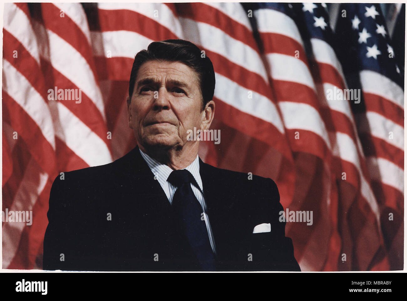 Le président Ronald Reagan parle de la tribune présidentielle devant une rangée de drapeaux américains Banque D'Images
