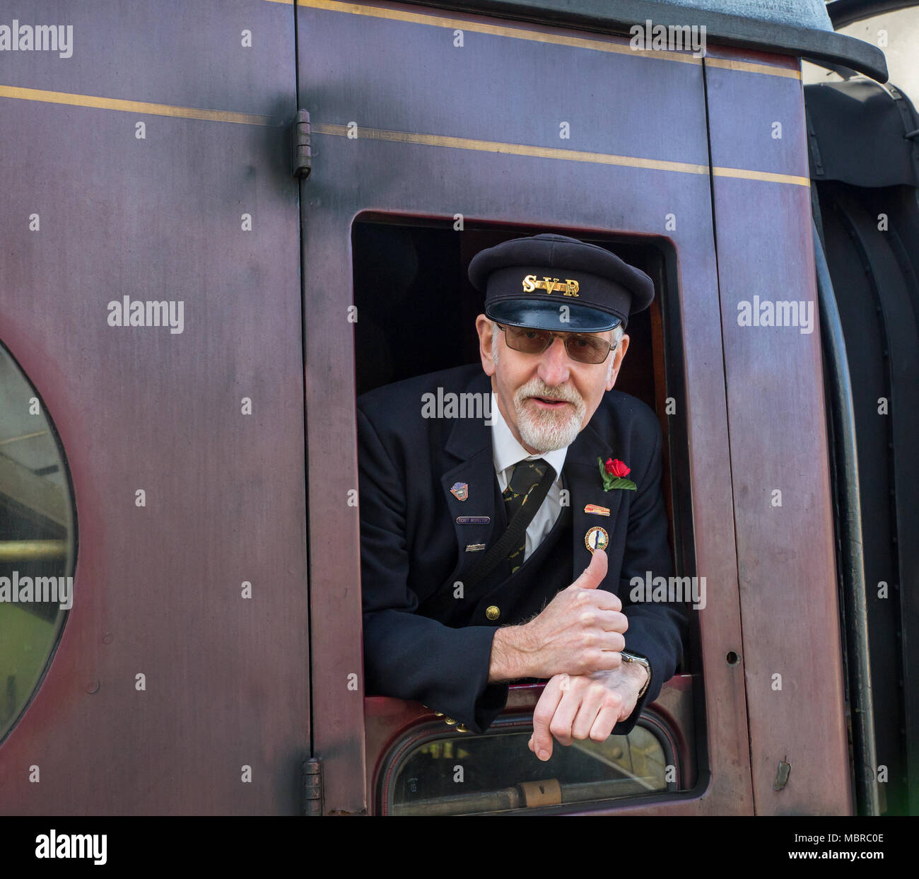 Close up of caucasian train principal gardien, de droits, de isolé vintage railway carriage fenêtre donnant un heureux 'Thumbs up'. Banque D'Images