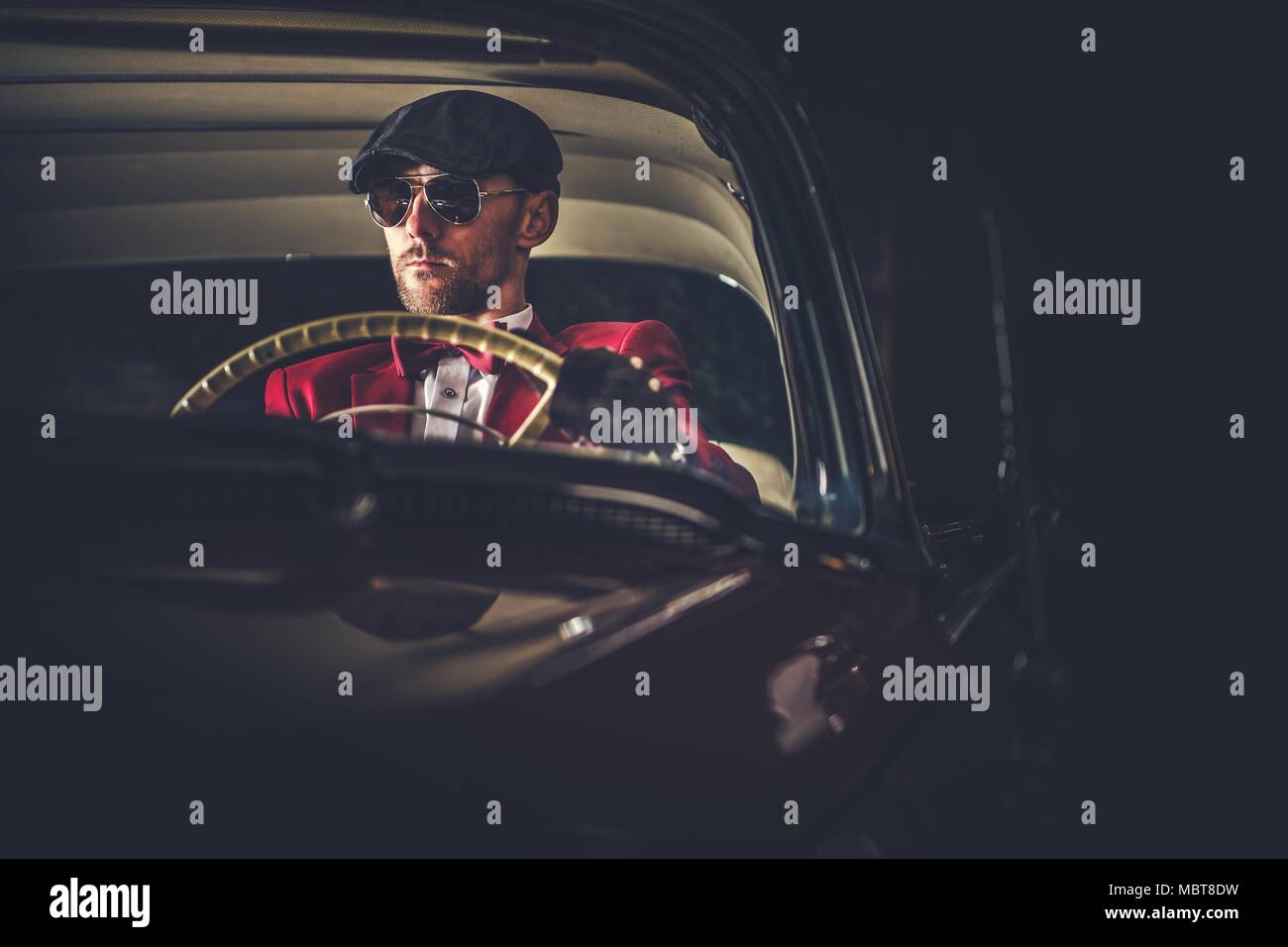 Conducteur de voiture Vintage caucasien élégant dans des lunettes de soleil. Au volant de sa voiture de passionné. Banque D'Images