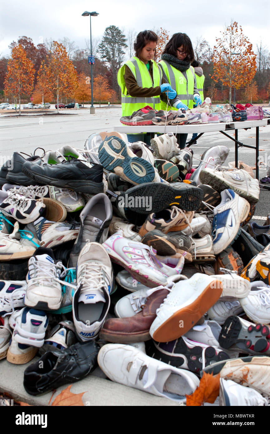 Deux jeunes bénévoles trier des chaussures de tennis avant de les jeter sur un tas de chaussures à être recyclés le 23 novembre 2013 à Lawrenceville, GA. Banque D'Images