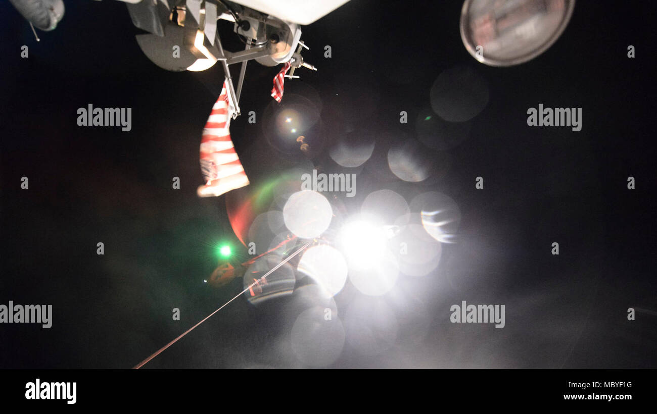 Une Garde côtière Air Station Humboldt Bay MH-65 équipage Dolphin survole un moteur de 47 pieds de la Garde côtière de sauvetage depuis Humboldt Bay durant la nuit, près d'Eureka formation treuil, Californie, le 6 mars 2018. Les équipages des hélicoptères de la Garde côtière canadienne effectuent couramment des équipages de petits bateaux avec formation de maintenir leurs qualifications et ainsi que dans le cas d'une évacuation sanitaire demande d'un bateau ou navire, les équipages sont compétents dans leurs techniques de sauvetage. (Garde côtière canadienne Banque D'Images