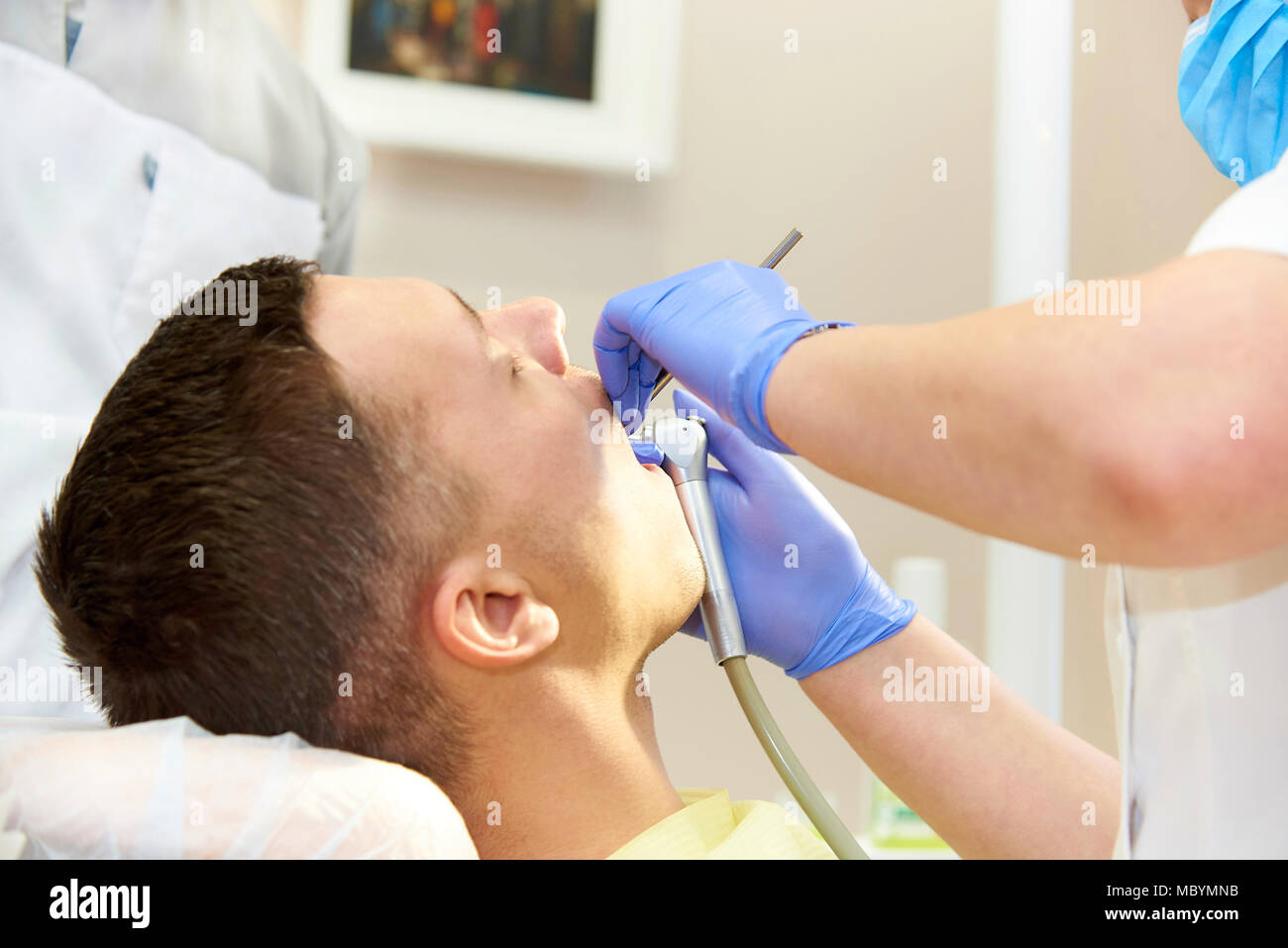 Mains de la dentiste dans gants bleu avec de l'équipement médical près de la bouche ouverte du patient. Banque D'Images