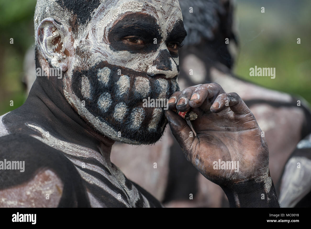 Un Masalai d'Omo avec squelette peinture sur visage de fumer la cigarette, le mont Hagen Spectacle culturel, Papouasie Nouvelle Guinée Banque D'Images