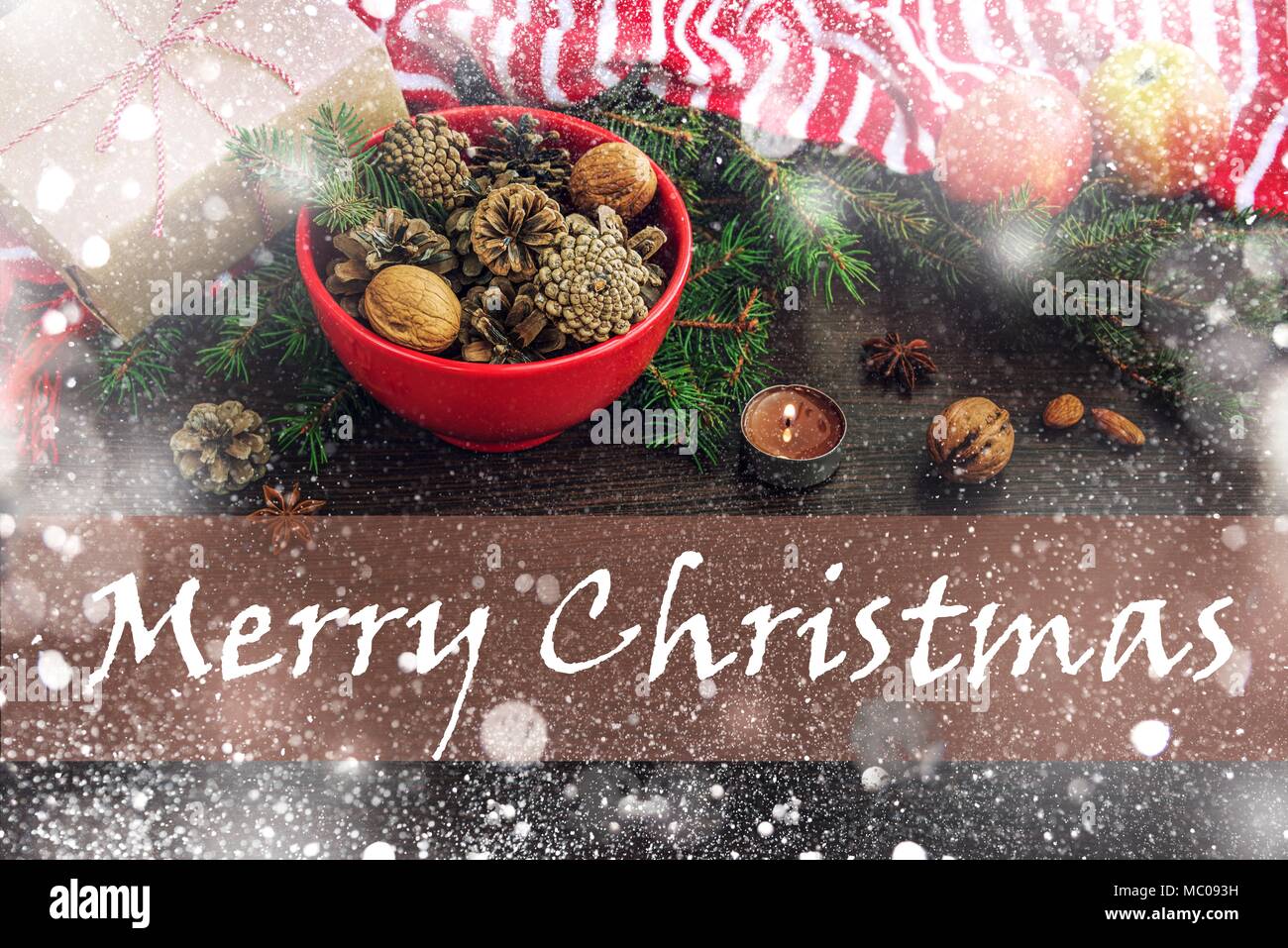 Décoration de Noël - rouge bol plein de cônes de sapin, boîte-cadeau enveloppé dans du papier kraft, des branches de pins, bougie, écrous, d'anis, pommes et bande rouge et blanc Banque D'Images