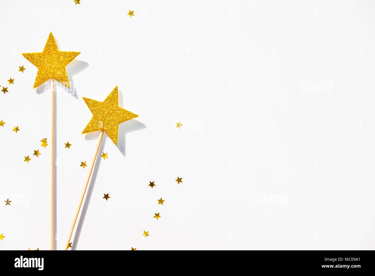Parti d'or deux baguettes magiques et de paillettes sur un fond blanc. Copier l'espace. Banque D'Images