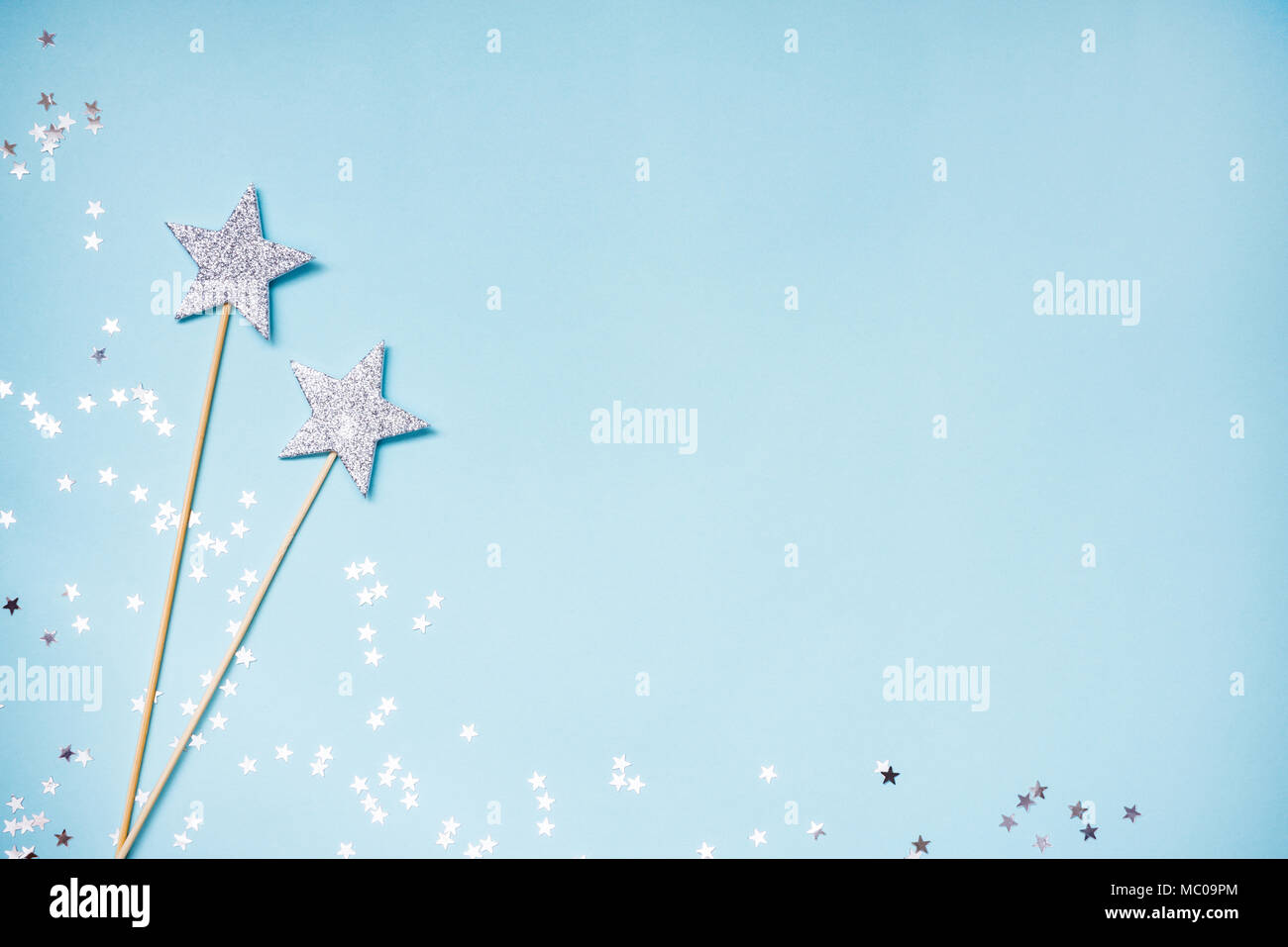 Deux d'argent partie baguettes magiques et paillettes éparpillées sur un fond bleu. Copier l'espace. Banque D'Images