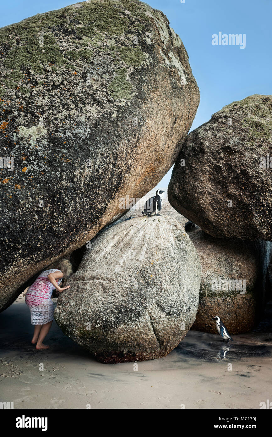 Parution modèle femme accroupie entre rochers géants sur une plage avec des pingouins africains, la plage de Boulders National Park, Simonstown, Afrique du Sud Banque D'Images
