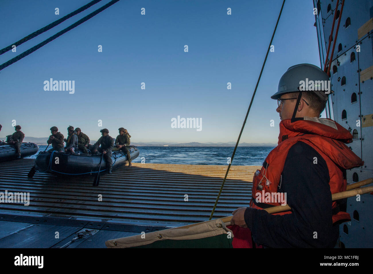 180122-N-RH181-202 OCÉAN PACIFIQUE (jan. 22, 2018) Seaman Spencer Englert drapeau donne des signaux à la neutralisation des explosifs et des plongeurs de l'Unité Mobile 3 pour lancer à l'arrière de la porte San Antonio-classe de transport amphibie USS dock Anchorage (LPD 23) avant le test de récupération, 22 janvier. Anchorage est en cours pour soutenir le vaisseau Orion de la NASA en cours Test de récupération (6 URT-6). (U.S. Photo par marine Spécialiste de la communication de masse 2e classe Carrel Regis) Banque D'Images