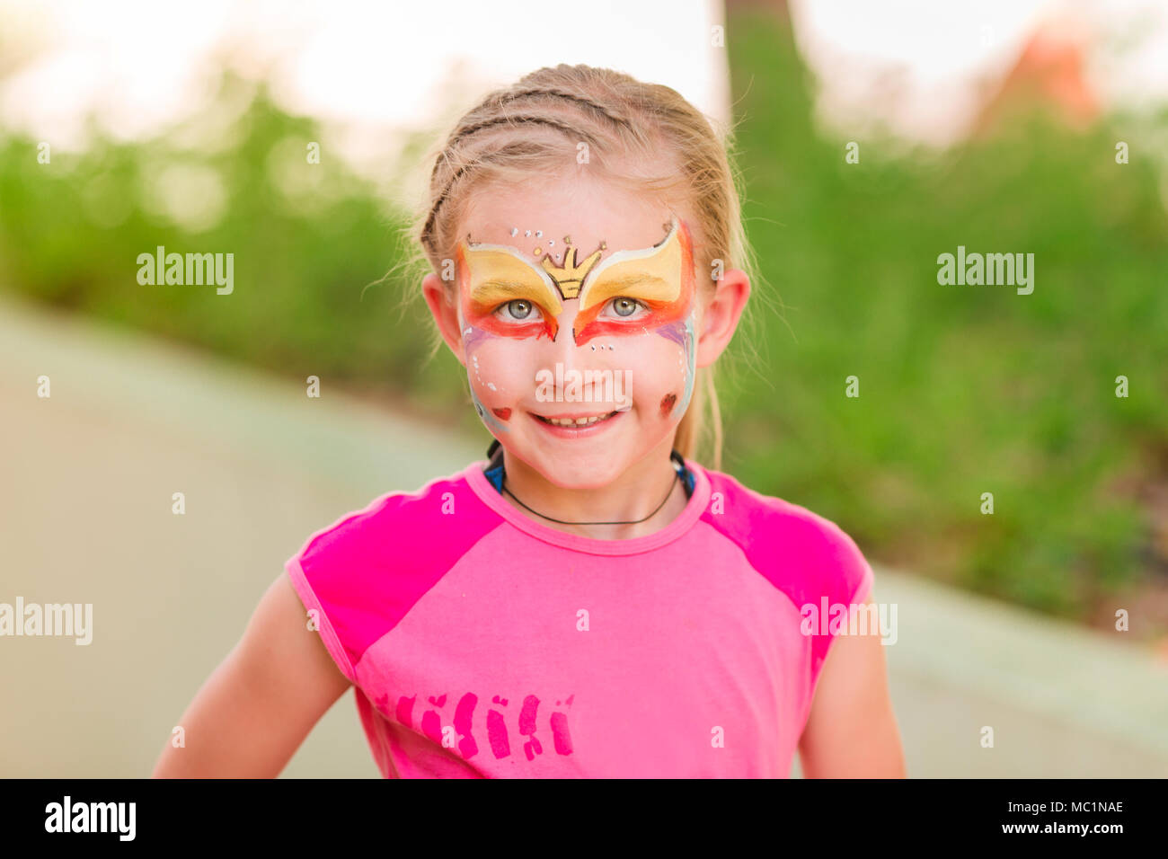 Happy little Girl with face peinture art dans le parc. Sa fête mascarade partie s'amuser, de rire. Loisirs et vacances. Banque D'Images