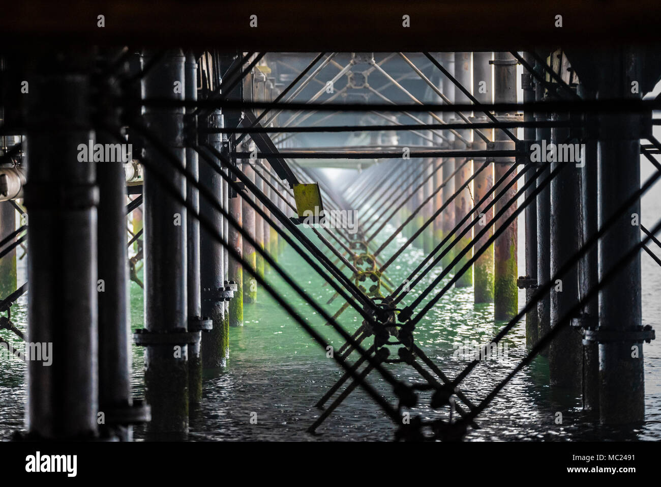 Jambe de fer de cadre structure en jetée de Southend L''estuaire de la Tamise. La corrosion, rouille rouge et vert de mer tide marques. Traverses de contreventement. En vertu de l'embarcadère. Eaux troubles Banque D'Images