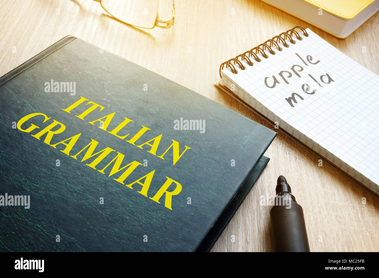 Apprendre la grammaire italienne. Livre et ordinateur portable sur une table. Banque D'Images