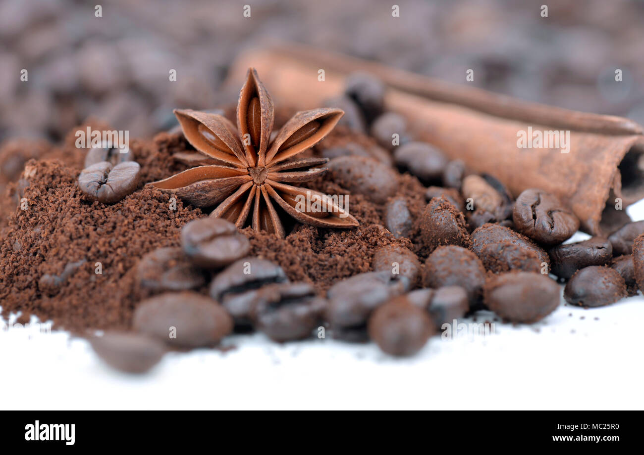 Fermer sur l'anis étoile parmi la cannelle et les grains de café sur fond blanc Banque D'Images