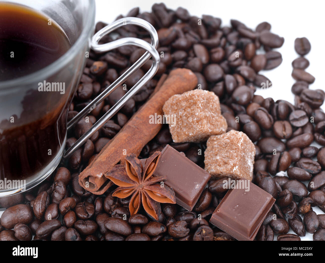 Grande tasse de café en grains de café, étoile d'anis, chocolat et sucre sur fond blanc Banque D'Images