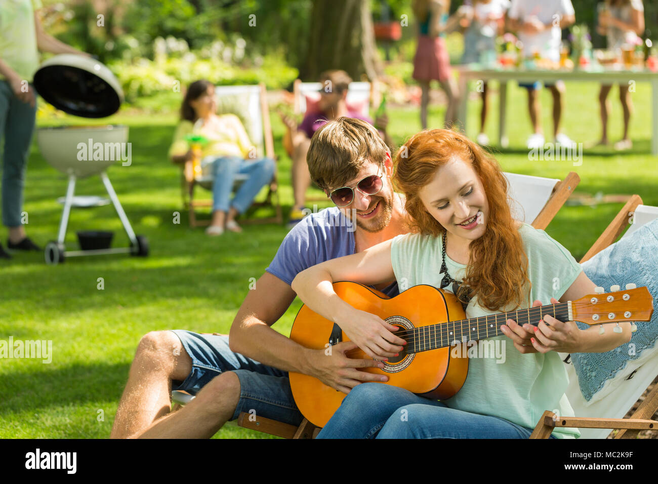 Jeune garçon enseigne la guitare redheaded petite amie en réunion avec des  amis Photo Stock - Alamy