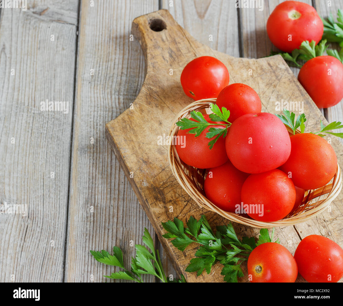 Les tomates rouges sur une planche en bois avec du persil. Mobilier de style Banque D'Images