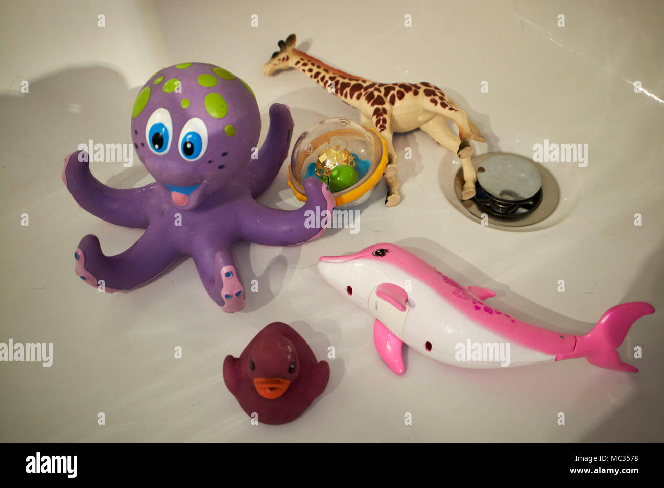 Les jouets d'enfant couché dans une baignoire vide Banque D'Images