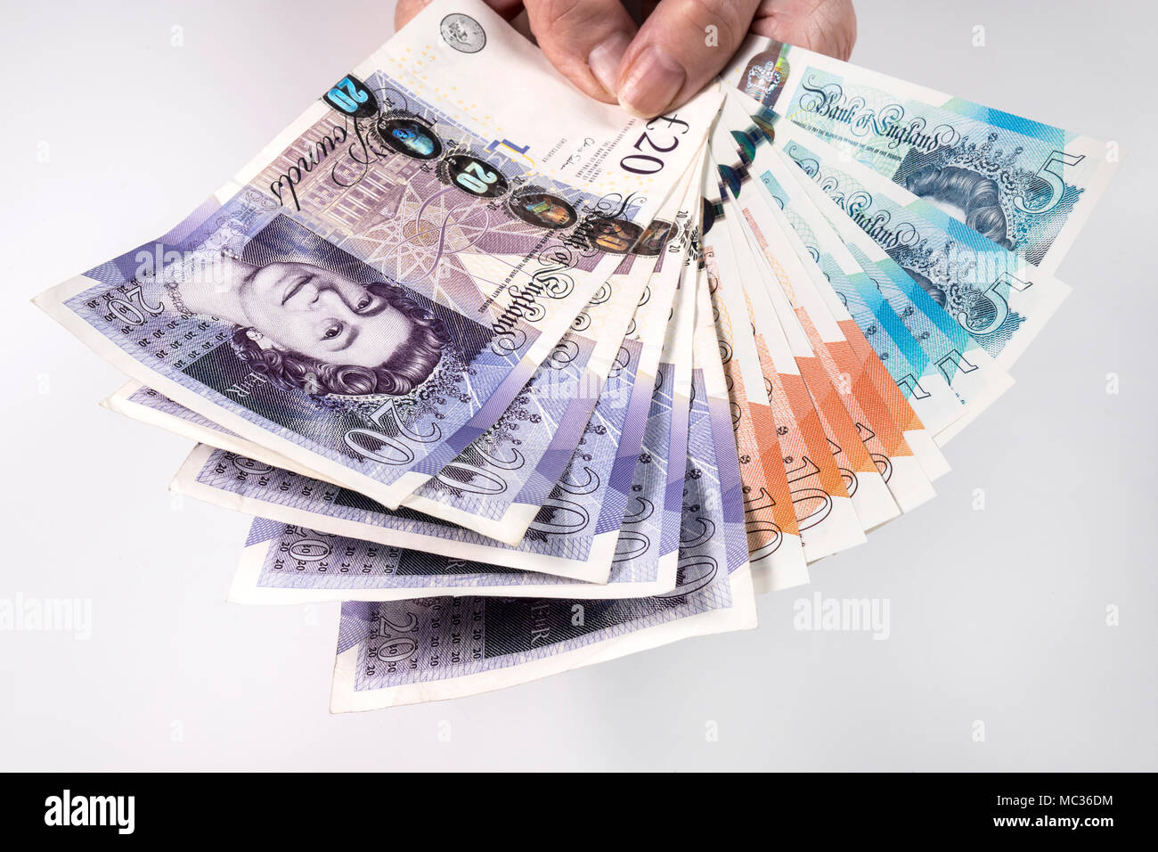 Une femme hand holding UK argent, £5 pound, £10 et £20 pound pound notes dans un ventilateur Banque D'Images