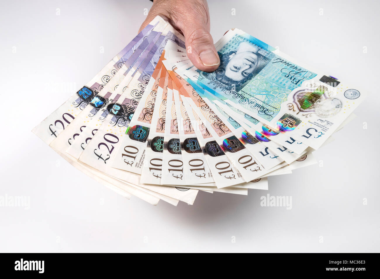 Une femme hand holding UK argent, £5 pound, £10 et £20 pound pound notes dans un ventilateur Banque D'Images
