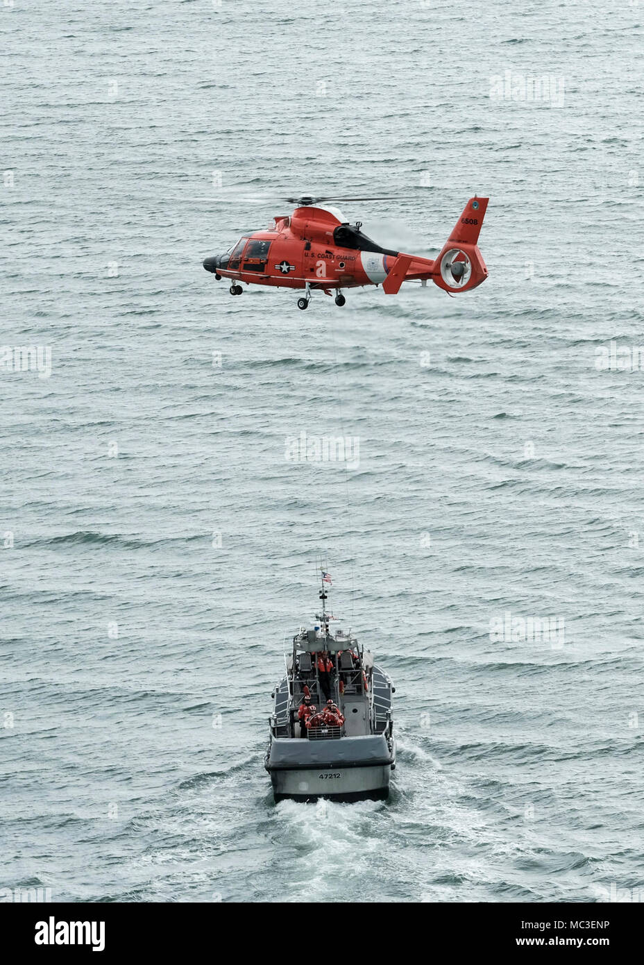 Un hélicoptère MH-65 de l'équipe de Dolphin Coast Guard Air Station Humboldt Bay plane au-dessus d'une embarcation à moteur de 47 pieds au cours de la formation de l'équipage à Eureka, Californie, le 7 mars 2018. Les équipages des hélicoptères de la Garde côtière canadienne effectuent couramment des équipages de petits bateaux avec formation de maintenir leurs qualifications et ainsi que dans le cas d'une évacuation sanitaire demande d'un bateau ou navire, les équipages sont compétents dans leurs techniques de sauvetage. Banque D'Images