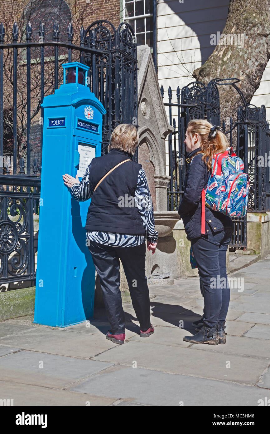 Ville de Londres un original police publique téléphone fort à St Martin's le Grand - touristes lire les 'plus' signe sur l'avant Banque D'Images