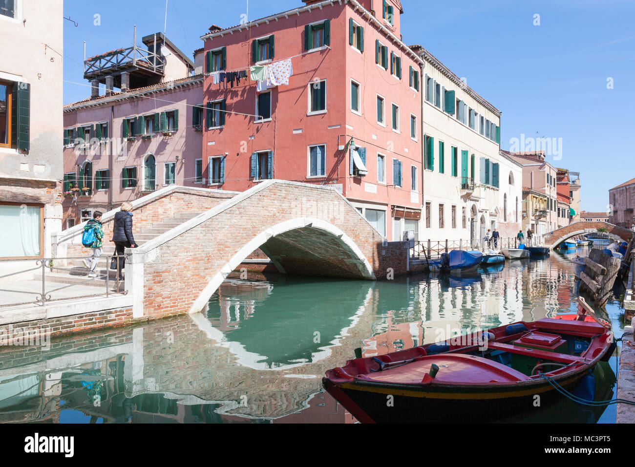 Ponte Nuovo Fondamentin sur Rios Sant'Anna, Castello, Venise, Vénétie, Italie avec des réflexions sur le paisible canal et bateau rouge Banque D'Images