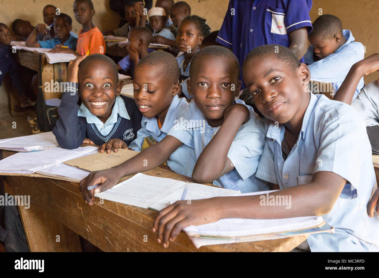 L'Ouganda. 13 juin 2017. Les enfants ougandais souriant assis à un bureau dans une salle de classe dans une école primaire. Banque D'Images