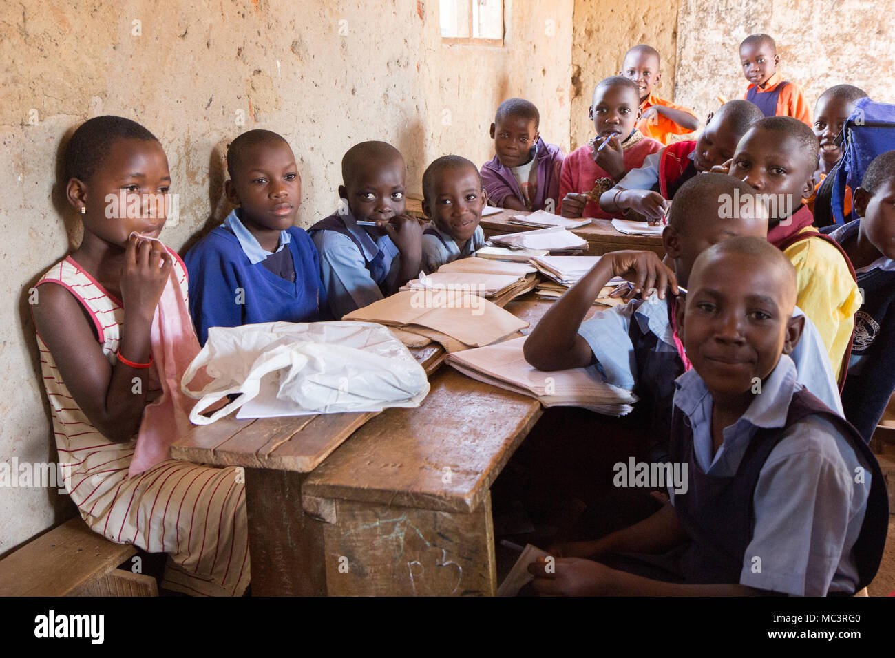 L'Ouganda. 13 juin 2017. Les enfants ougandais souriant assis à un bureau dans une salle de classe dans une école primaire. Banque D'Images
