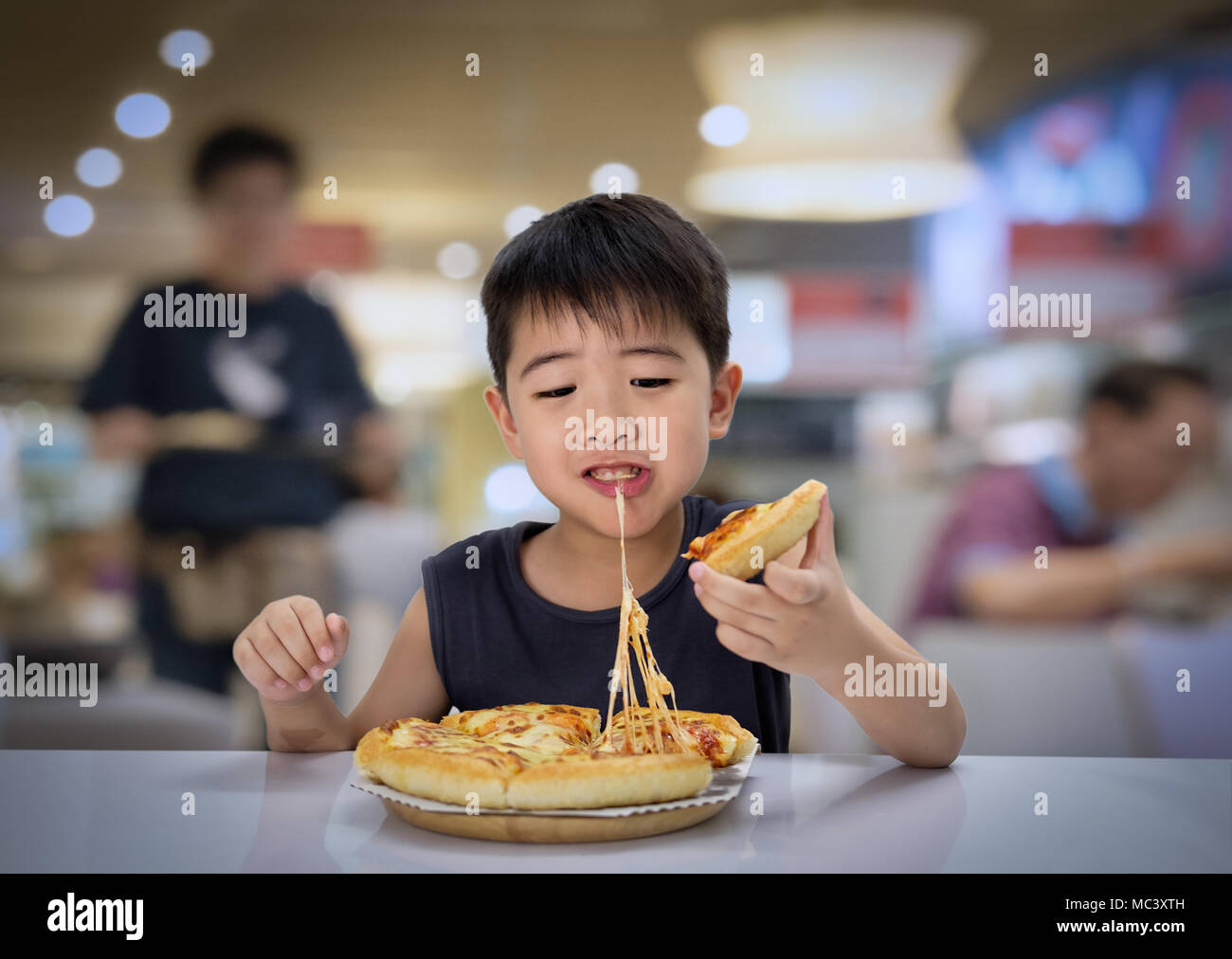 6-7 ans garçon asiatique est heureux de manger la pizza avec une chaude  faire fondre le fromage, tendue sur un tampon en bois dans le restaurant  Photo Stock - Alamy