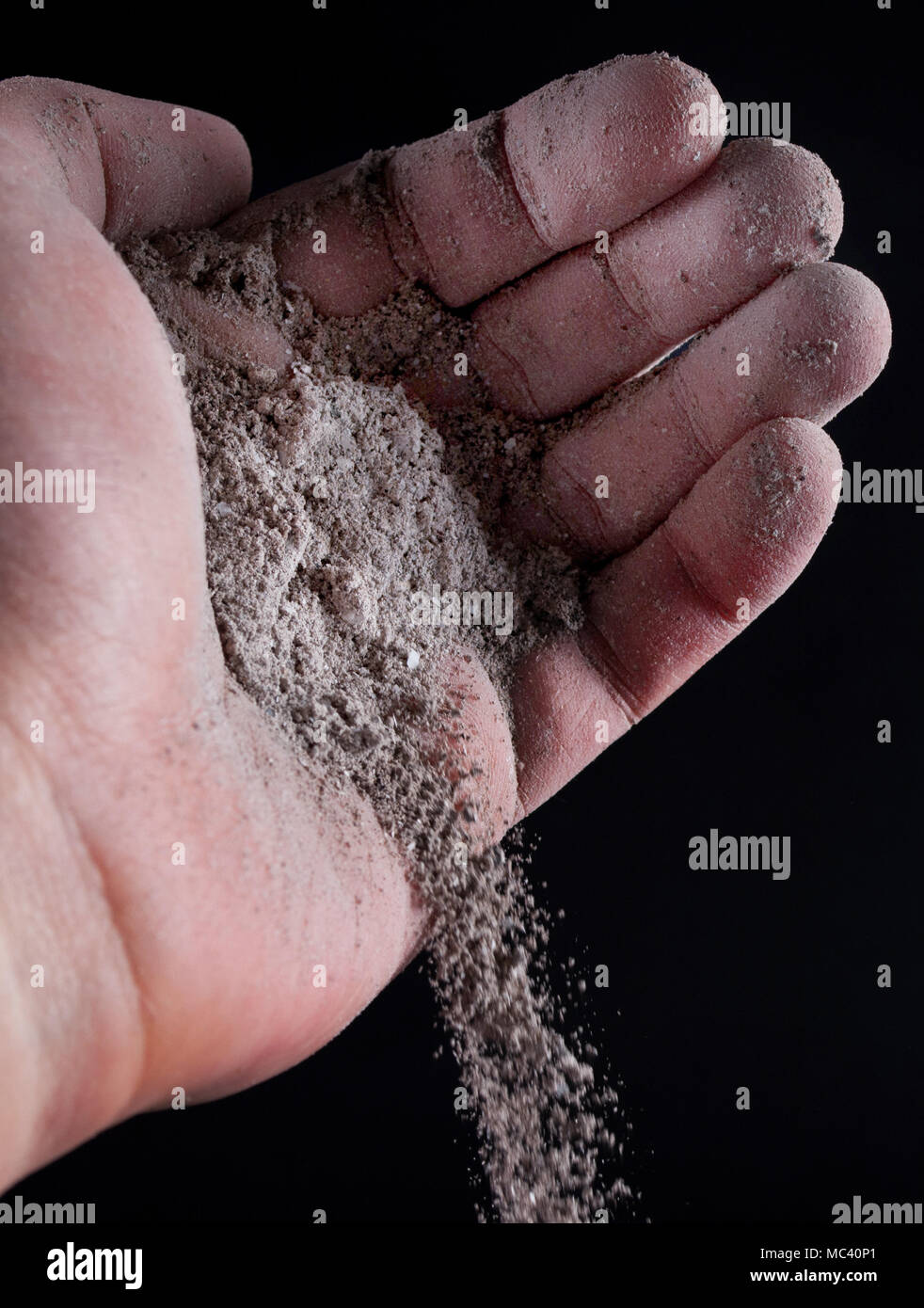 Frêne gris verser hors de la main de l'homme isolé sur noir. Close up. Selective focus Banque D'Images