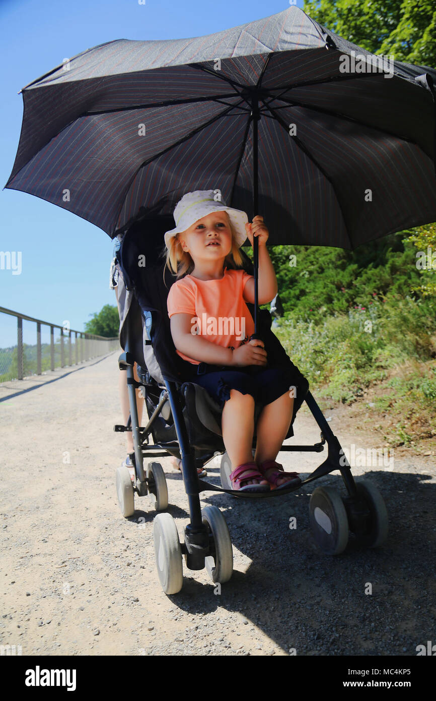 Petite fille assise dans la poussette. Enfant du Soleil par grand parapluie.  Coup de chaleur sur la prévention pour enfants journée ensoleillée en été  Photo Stock - Alamy