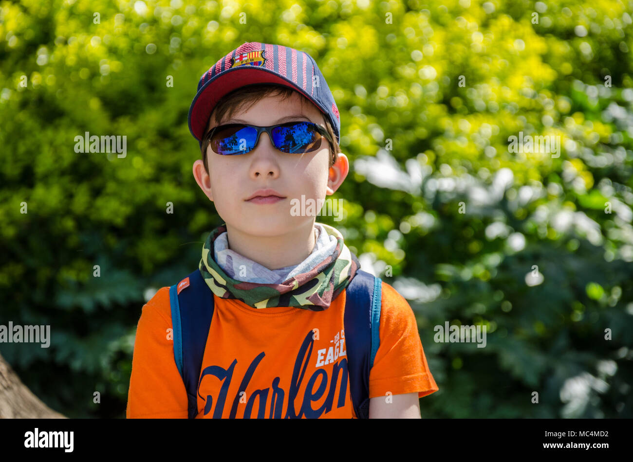 Le portrait d'un garçon de 8 ans, portant des lunettes de soleil et une casquette de baseball. Banque D'Images