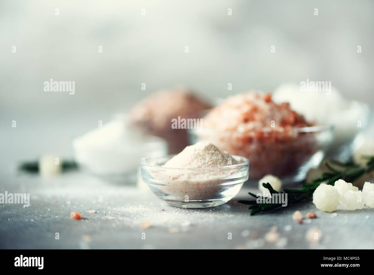 Mélange de différents types de sel sur fond de béton gris. Les sels de mer, noir et rose de l'himalaya sels cristaux, poudre, romarin. Boules de cristal de sel de mer morte. Copy space Banque D'Images