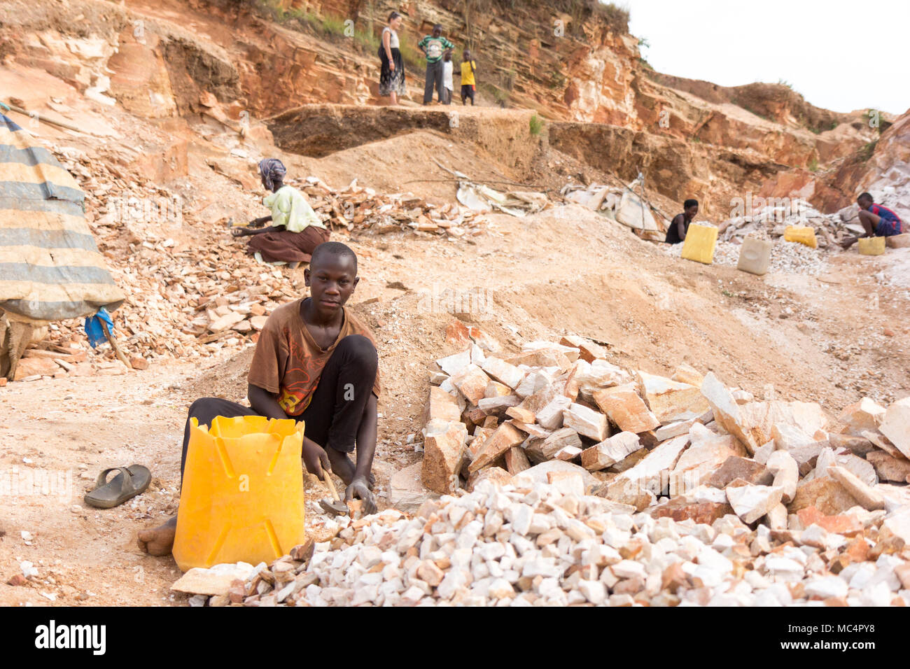 Lugazi, en Ouganda. 18 juin 2017. Un garçon ougandais casser des pierres dans les petites dalles à son contremaître. Fondamentalement, le travail des enfants. Banque D'Images
