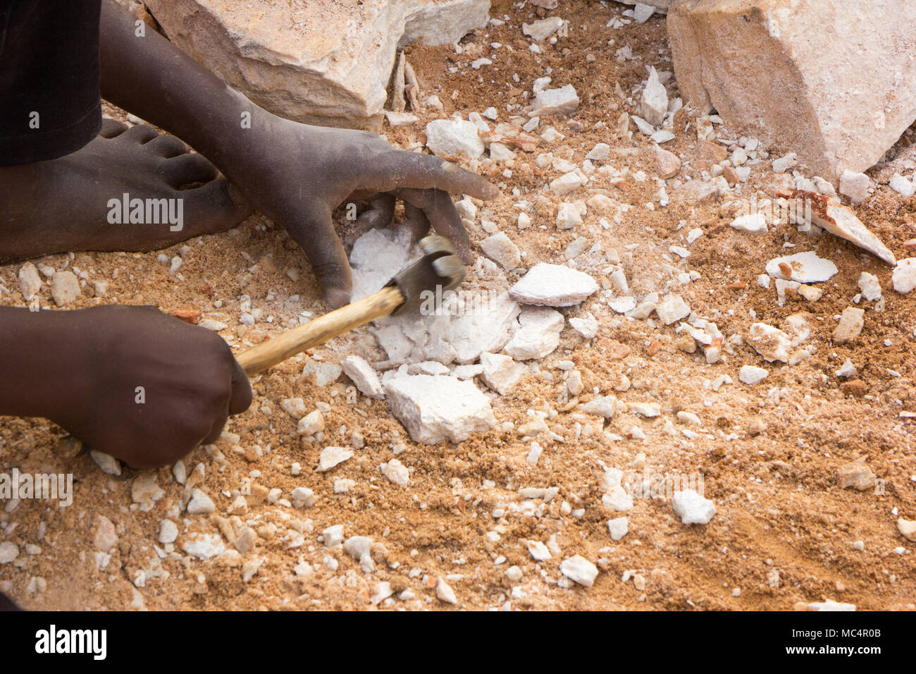 Les mains de l'enfant ougandais casser des pierres dans les petites dalles à son contremaître. Tourné en Ouganda en juin 2017. Banque D'Images