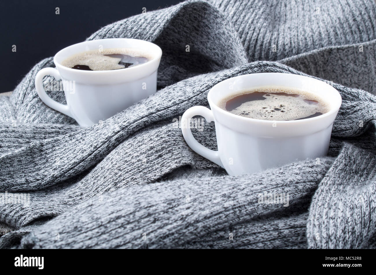 Deux tasses de café chaud dans les plis d'une écharpe gris close-up avec une faible profondeur de foyer Banque D'Images