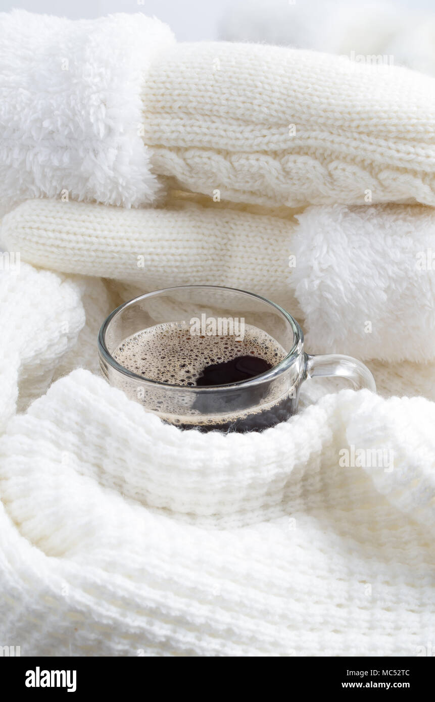 Mug en verre transparent avec du café chaud enveloppé dans une écharpe de laine blanche avec une faible profondeur de foyer. Banque D'Images