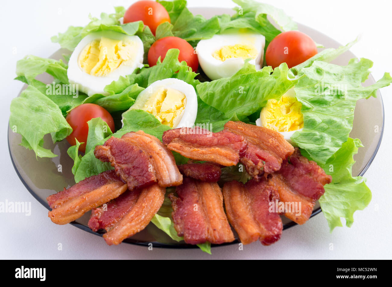 Salade, tomates cerises, du bacon et des œufs sur une plaque close-up avec une faible profondeur de foyer Banque D'Images
