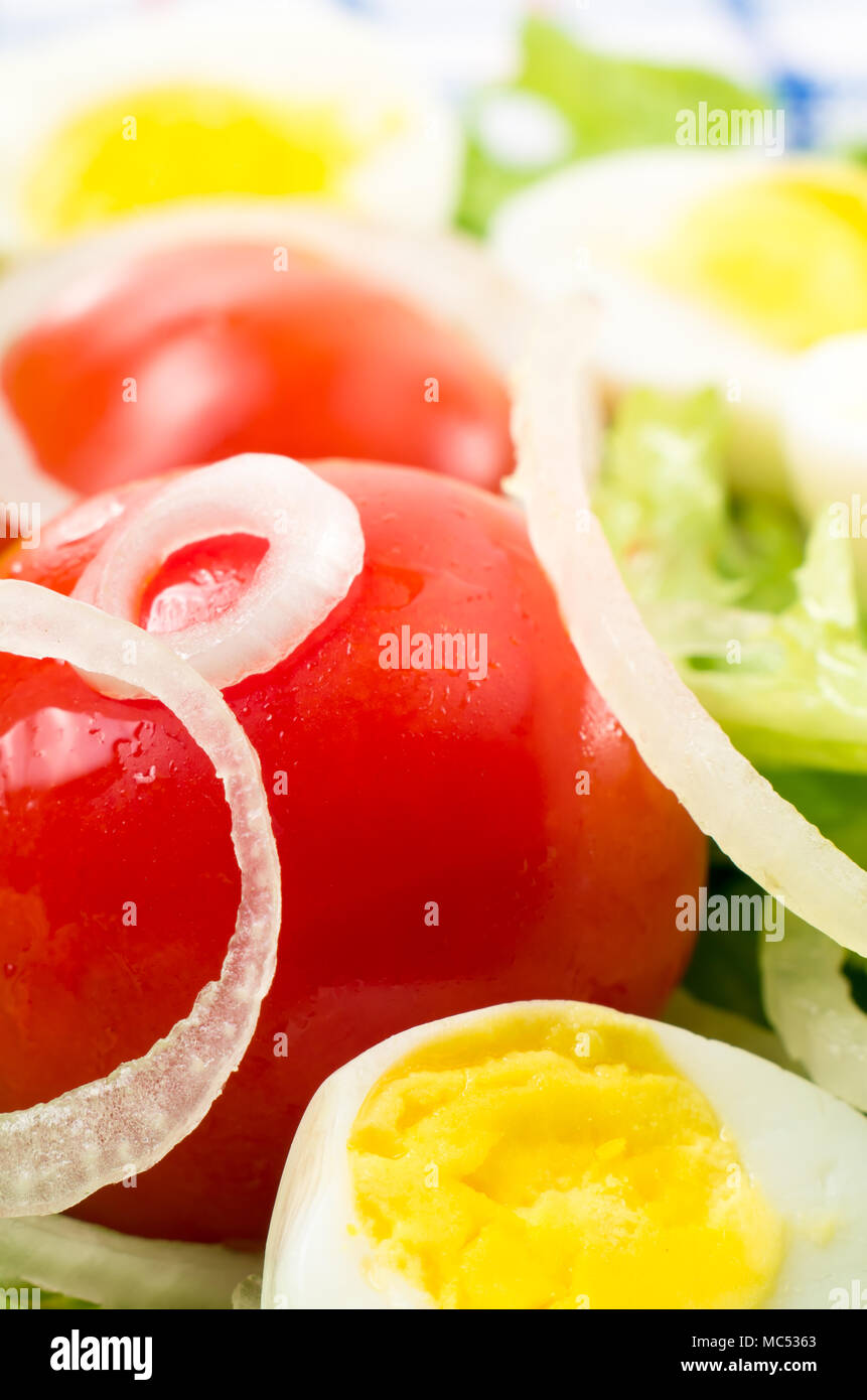 Les tomates cerises et les œufs durs dans une salade de feuilles de laitue, d'huile d'olive et les oignons libre avec une petite profondeur de champ Banque D'Images