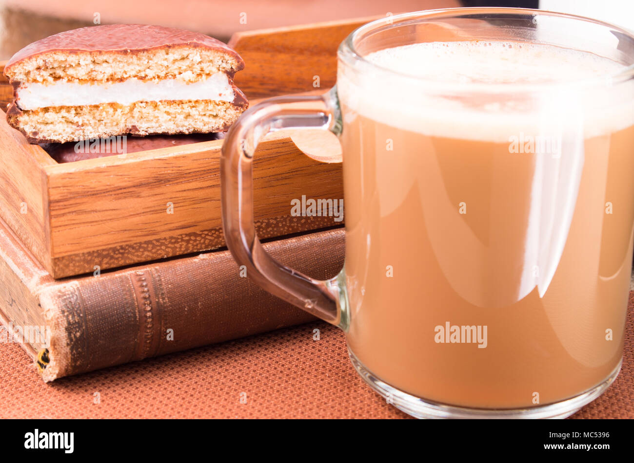 Mug en verre avec du chocolat chaud et des biscuits dans un plateau en bois sur un gros plan de table marron. Arrière-plan flou et profondeur de champ Banque D'Images