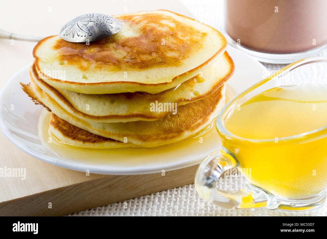 Crêpes russes avec du miel et vintage cuillère en argent sur une plaque blanche pour un petit-déjeuner sucré avec une faible profondeur de champ Banque D'Images