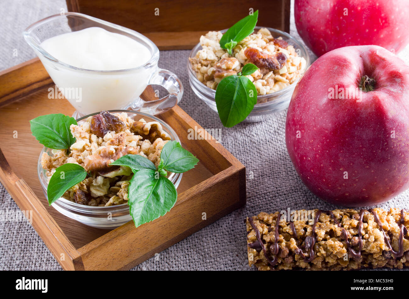 Des produits utiles pour le petit-déjeuner. Muesli aux noix et raisins secs, de pommes et de yaourt sur une nappe gris closeup Banque D'Images