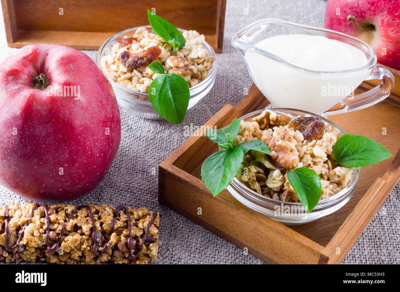 Des aliments sains pour le petit déjeuner. Céréales d'avoine avec des noix et des raisins secs, de pommes et de yaourt sur une nappe gris closeup Banque D'Images