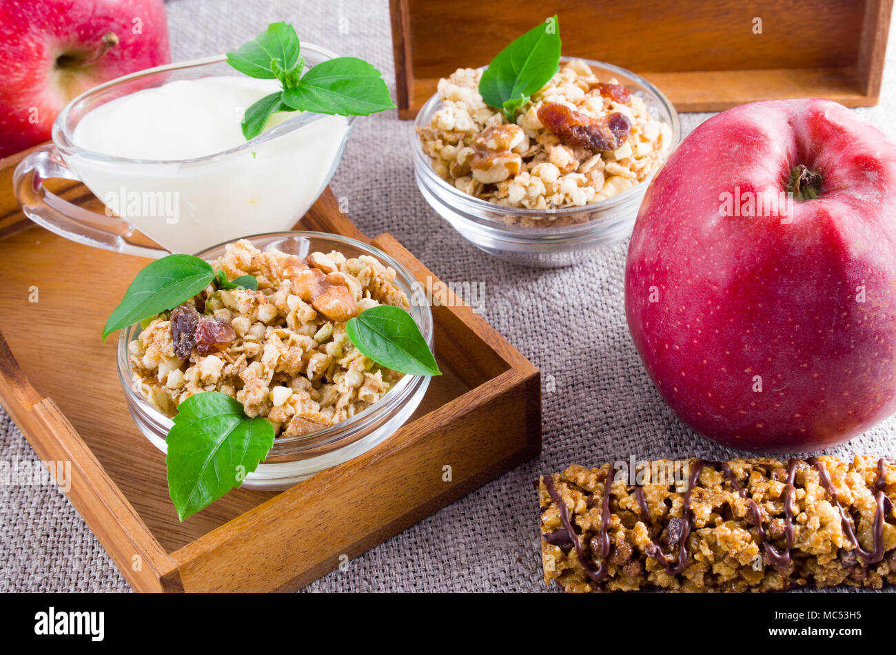 Des aliments sains pour le petit déjeuner. Céréales d'avoine avec des noix et des raisins secs, de pommes et de yaourt sur une nappe gris closeup Banque D'Images