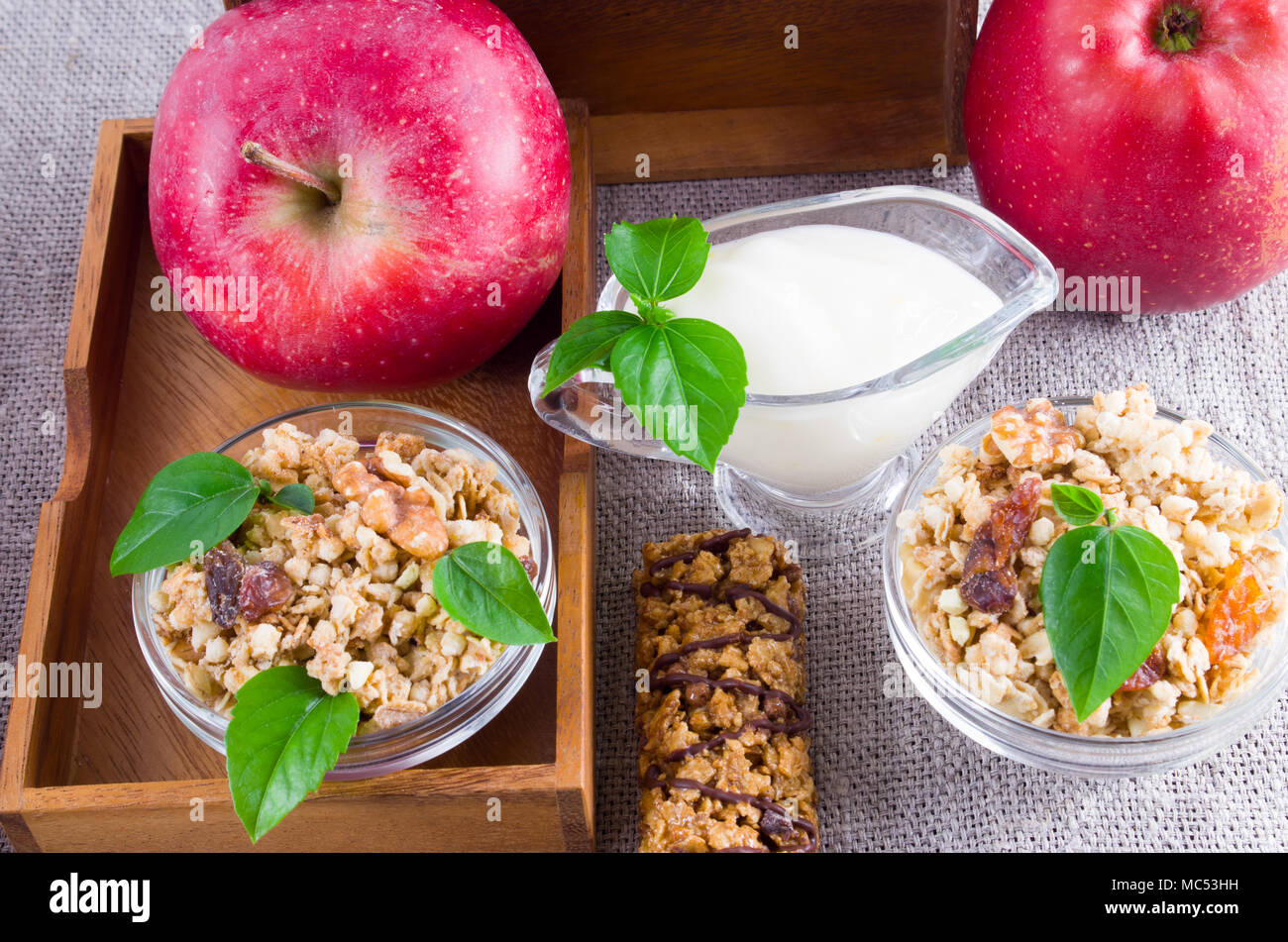 Des ingrédients sains pour le petit déjeuner. Céréales d'avoine avec des noix et des raisins secs, de pommes et de yaourt sur une nappe gris closeup Banque D'Images